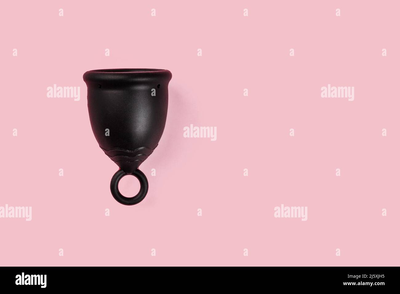 Tasse en silicone menstruelle noire sur fond rose. Produit d'hygiène alternatif pour femmes Banque D'Images