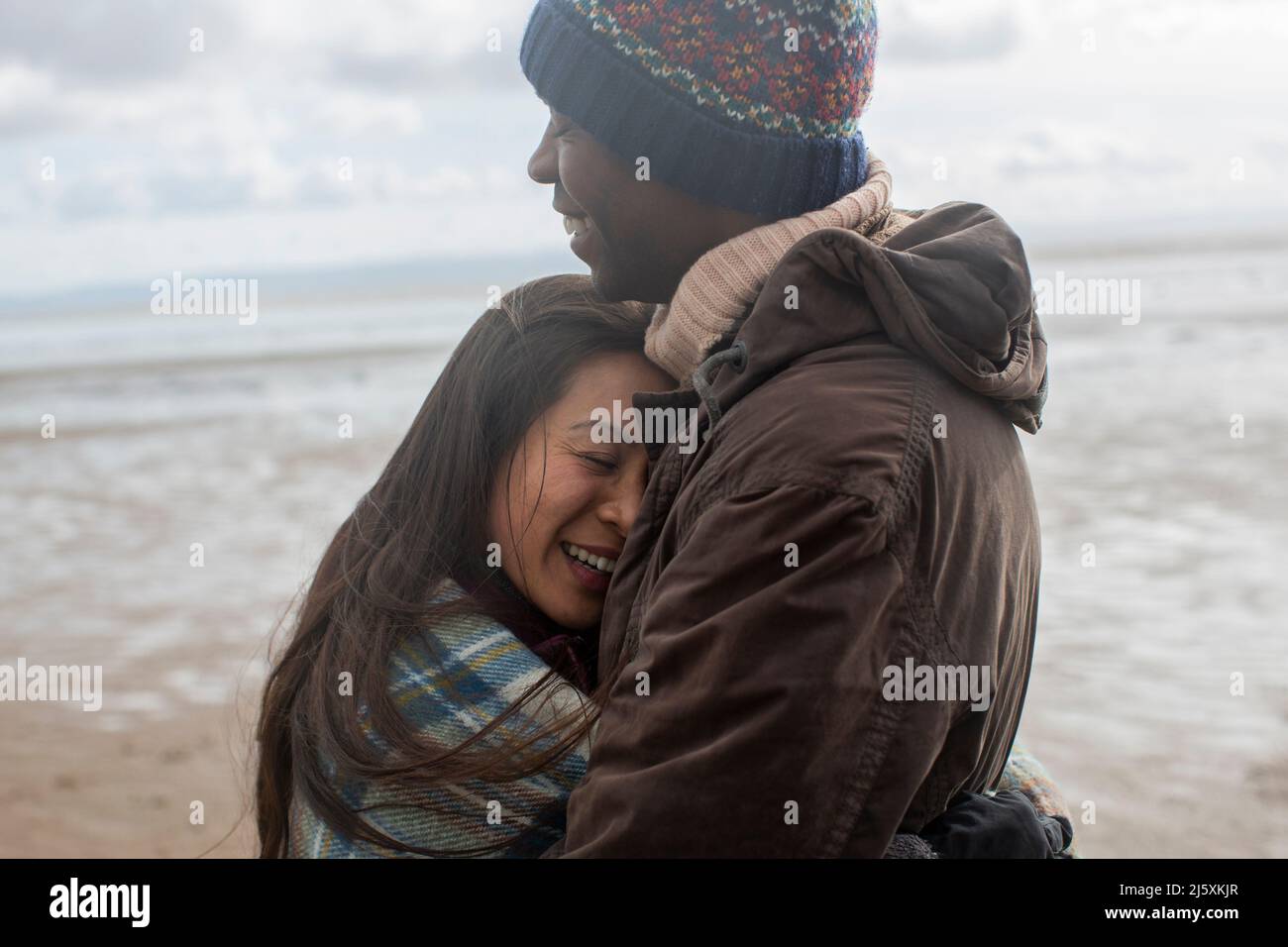 Couple affectueux et heureux qui s'enserre sur la plage d'hiver Banque D'Images