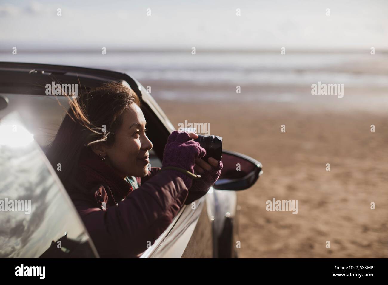 Femme avec appareil photo numérique convertible sur la plage Banque D'Images