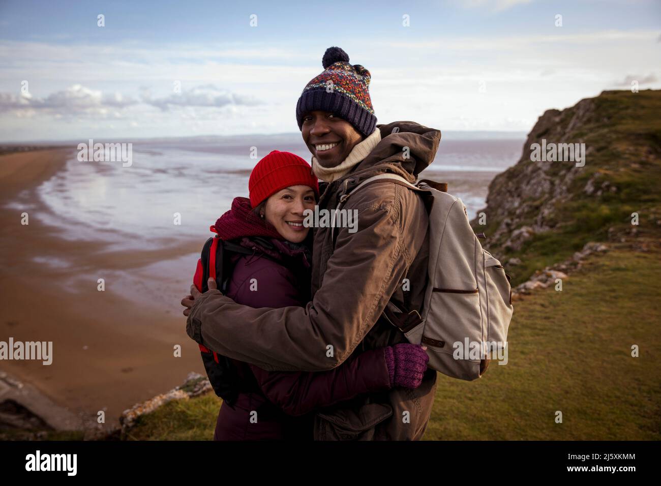 Portrait heureux. Couple de randonneurs embrassant sur la falaise surplombant la plage Banque D'Images