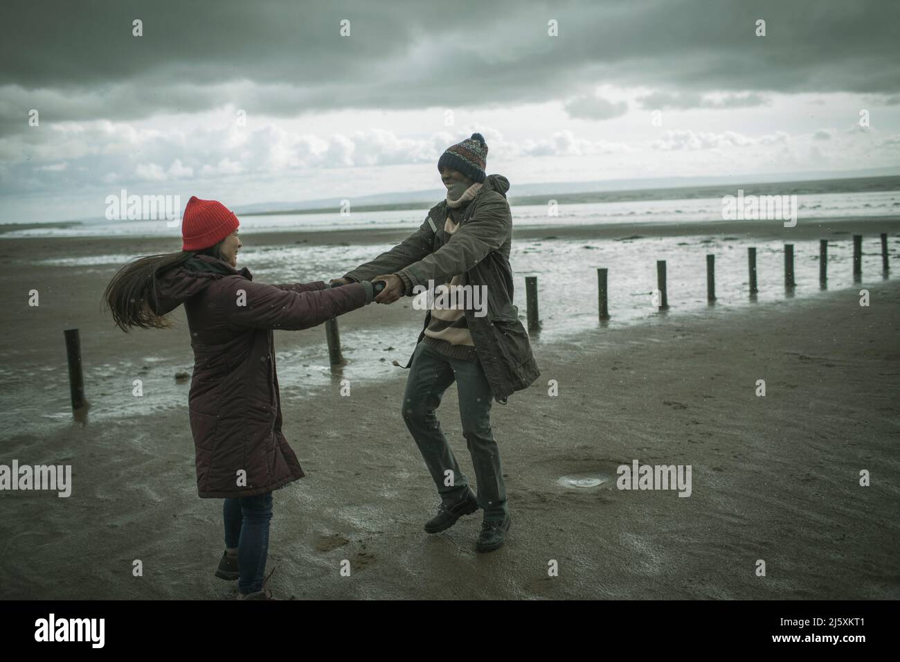 Joyeux couple amusant tenant la main sur la plage d'hiver Banque D'Images