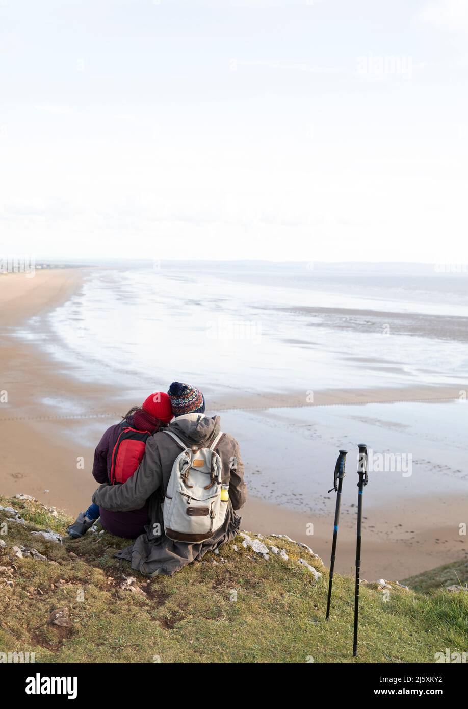 Couple de randonneurs affectueux qui s'embrasse sur une falaise avec vue sur la plage Banque D'Images