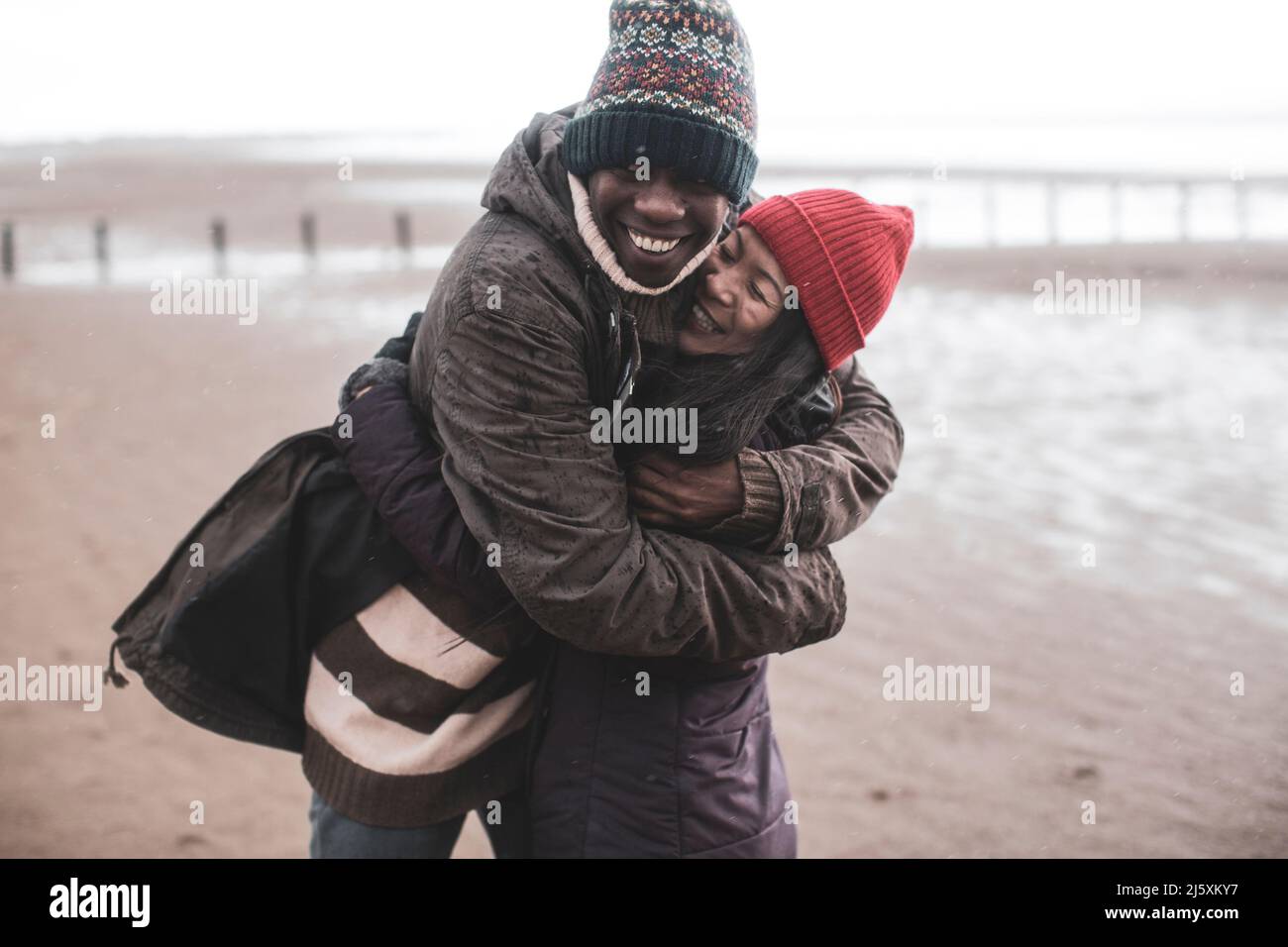 Joyeux couple enjoué sur la plage humide d'hiver Banque D'Images