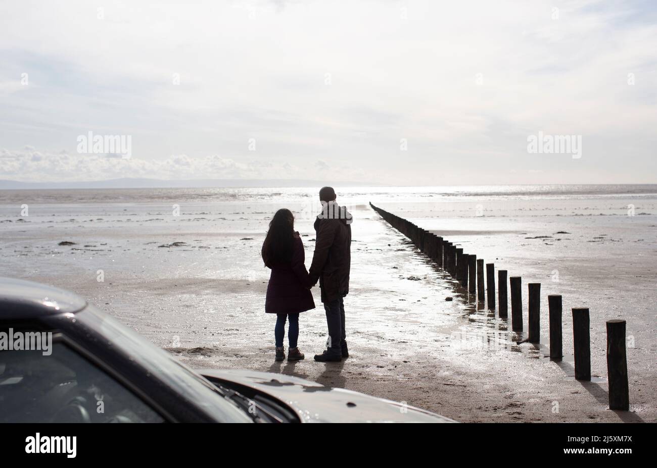 Couple silhouette sur une plage d'hiver humide et ensoleillée Banque D'Images