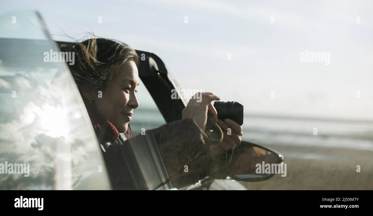 Femme avec appareil photo numérique convertible sur la plage d'hiver Banque D'Images