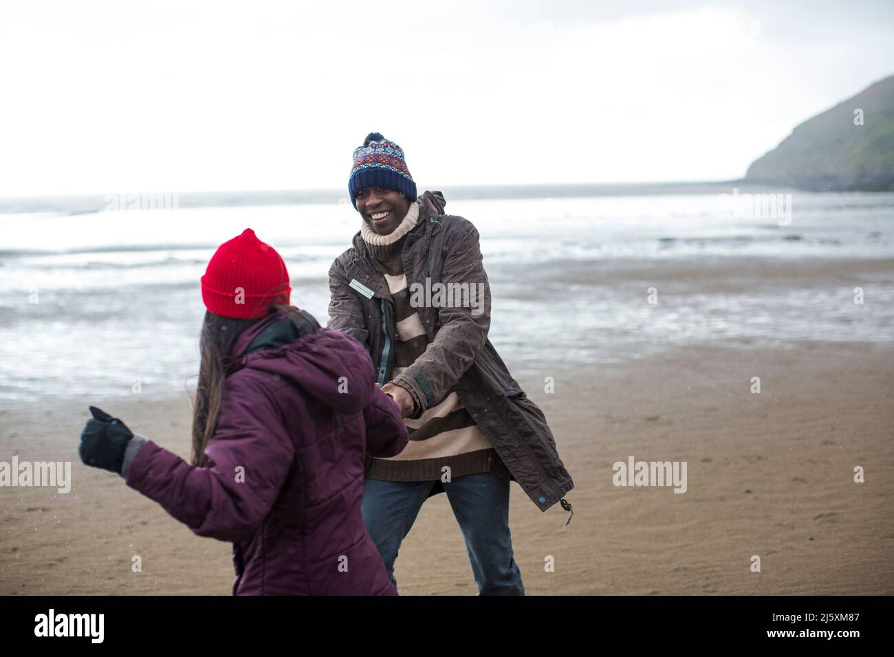 Couple joyeux sur la plage humide d'hiver Banque D'Images