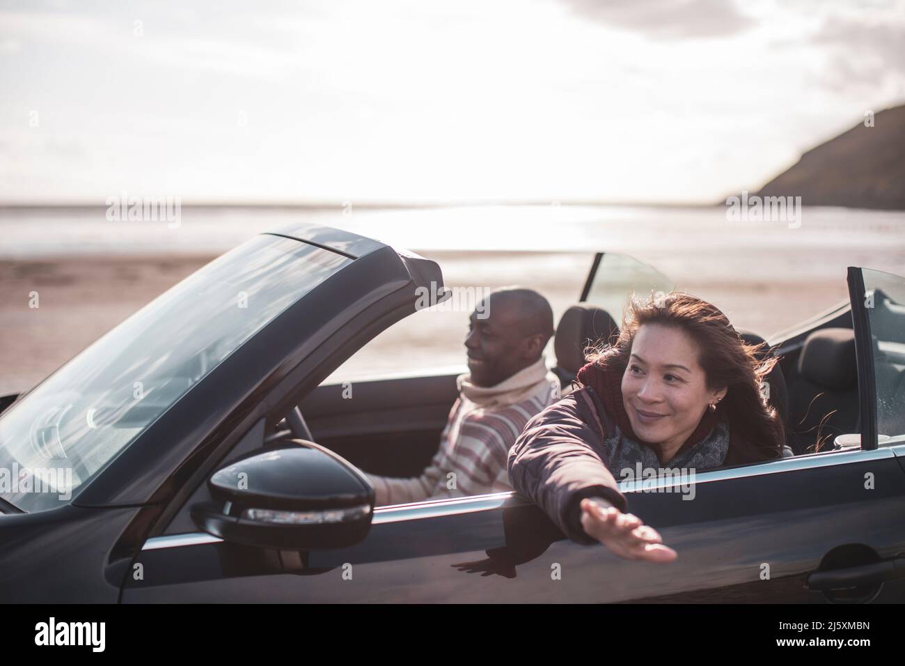 Couple insouciant en voiture dans le cabriolet sur la plage d'hiver Banque D'Images
