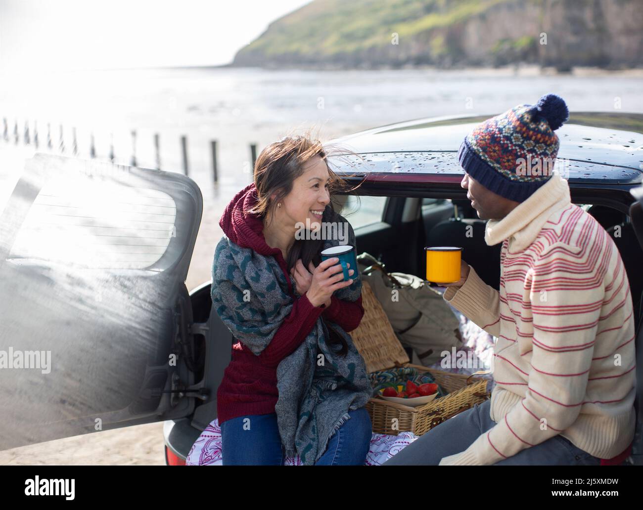 Bon couple qui boit du café à l'arrière de la voiture sur la plage Banque D'Images