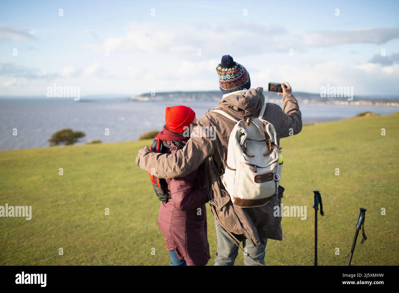 Un couple de randonneurs avec un téléphone avec caméra sur la falaise avec vue ensoleillée sur l'océan Banque D'Images
