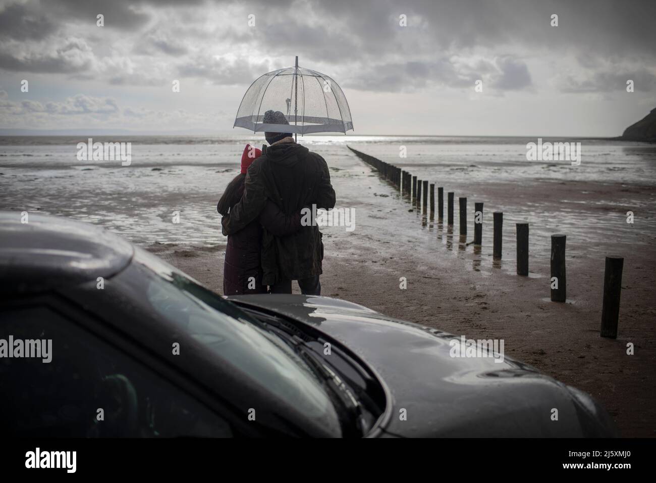 Couple sous un parapluie sur une plage d'hiver humide Banque D'Images