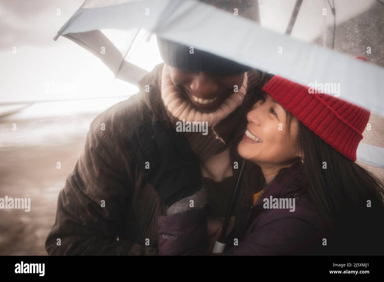 Couple heureux sous parapluie sur la plage humide d'hiver Banque D'Images