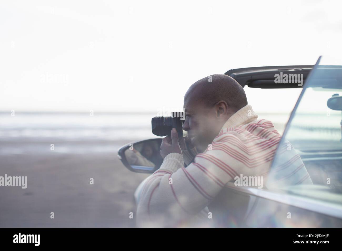 Homme avec un appareil photo numérique convertible sur la plage d'hiver Banque D'Images