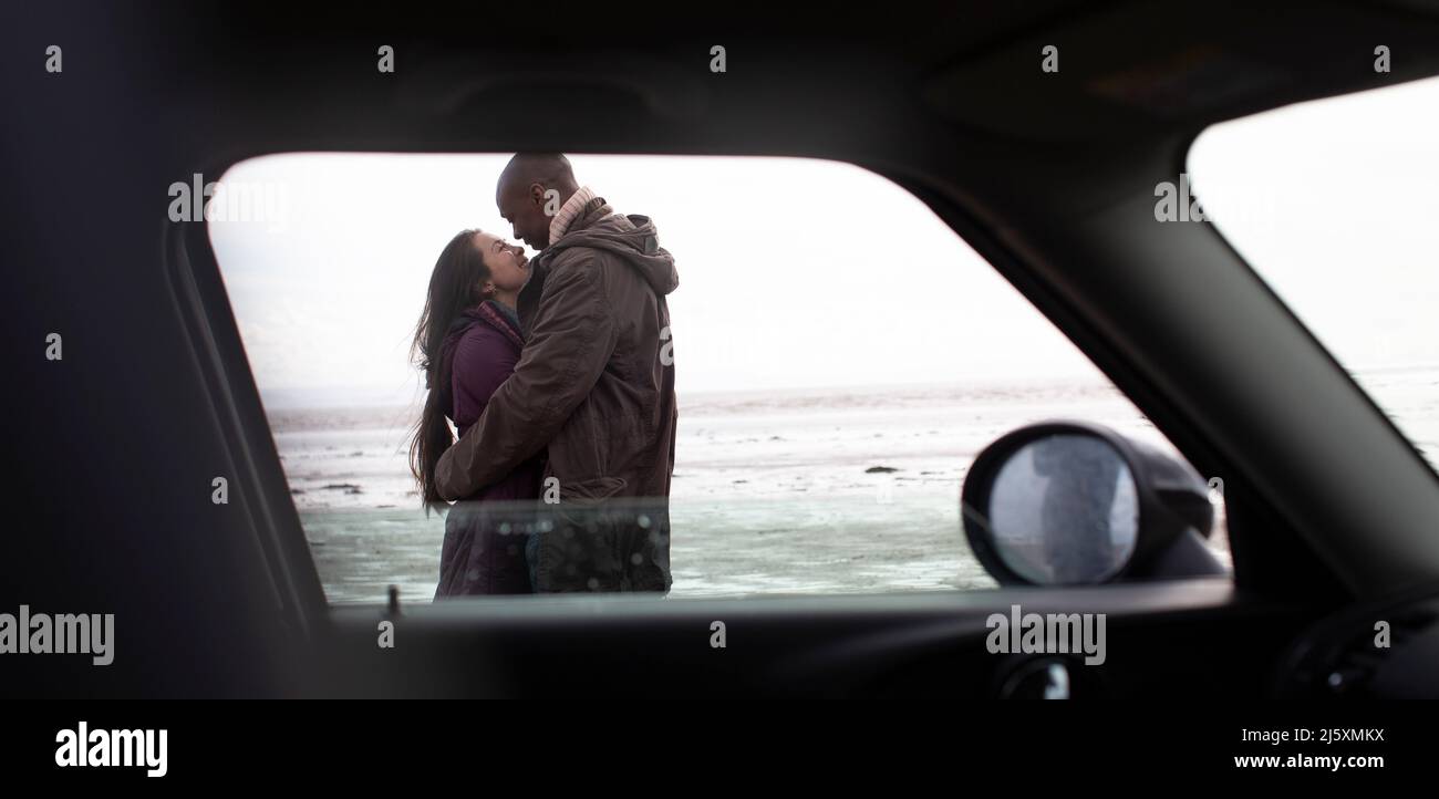 Couple qui s'embrasse en voiture sur la plage d'hiver Banque D'Images