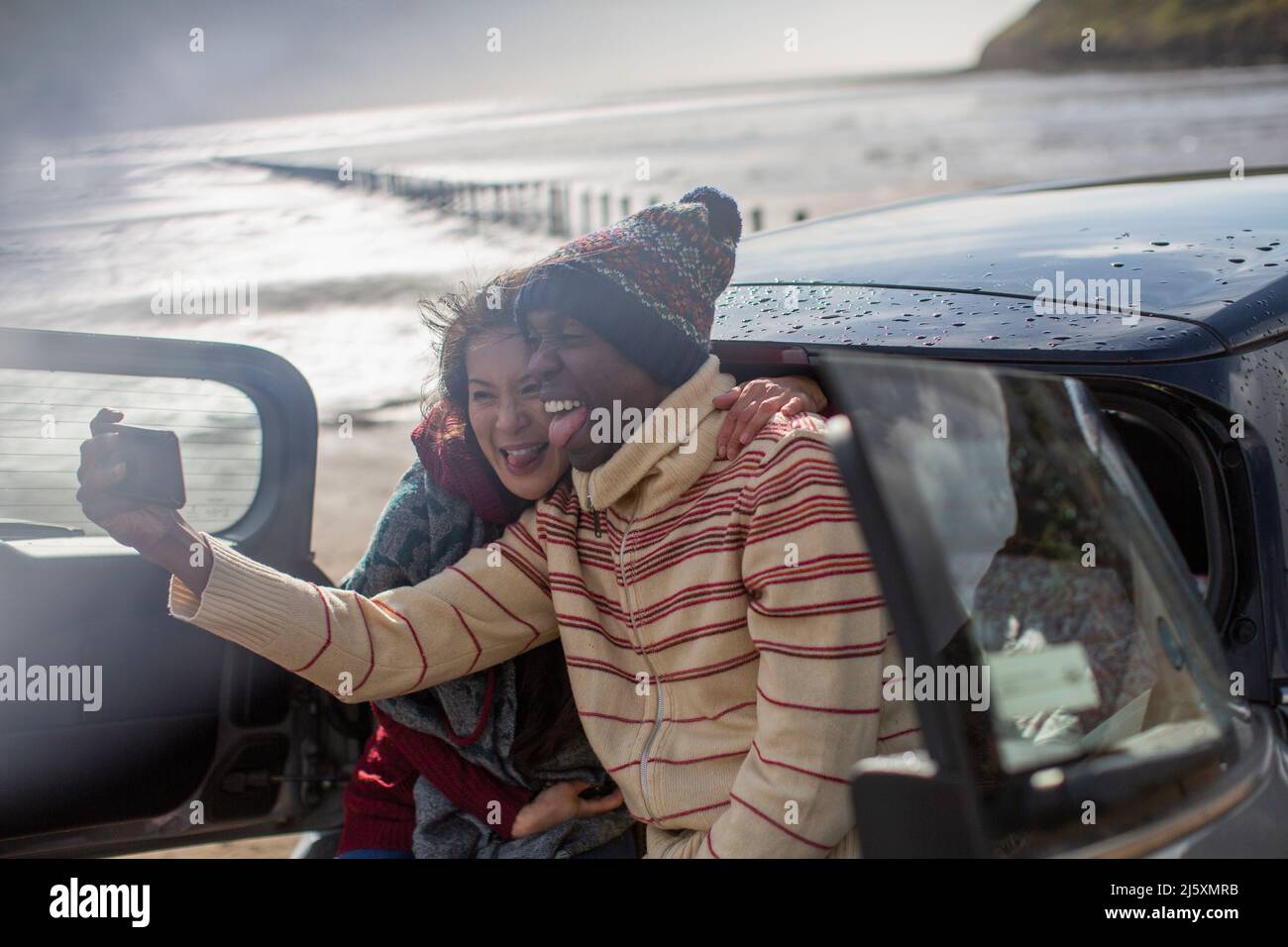 Un couple joyeux et amusant prend le selfie en voiture sur la plage d'hiver Banque D'Images