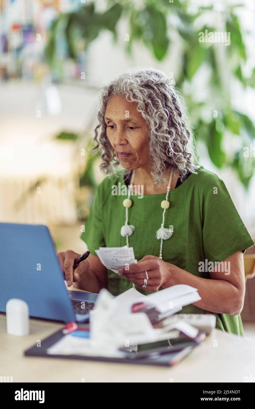 Femme âgée avec budget de reçus sur ordinateur portable Banque D'Images