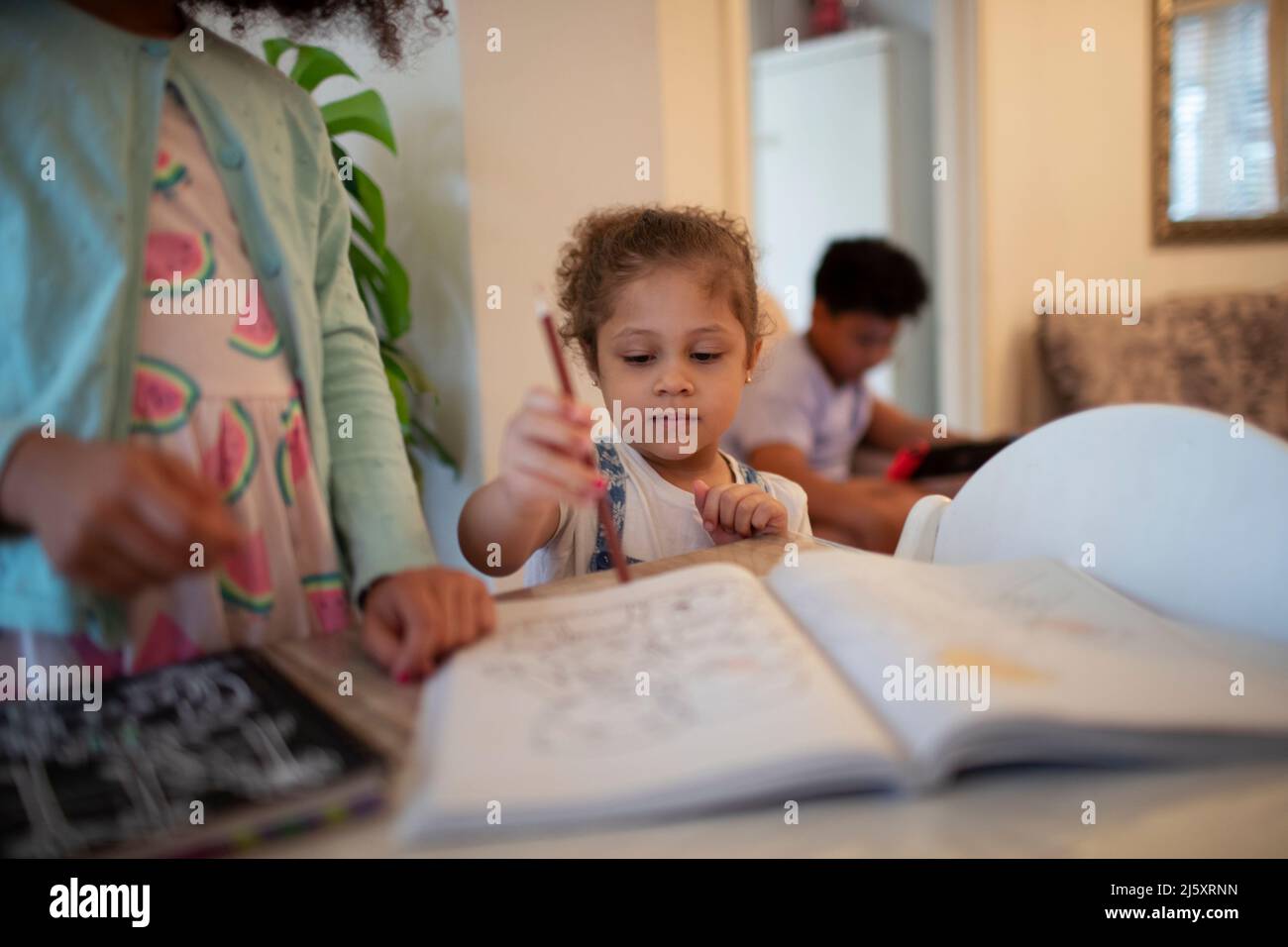 Jolie fille colorant dans le livre de coloriage avec crayon de couleur Banque D'Images