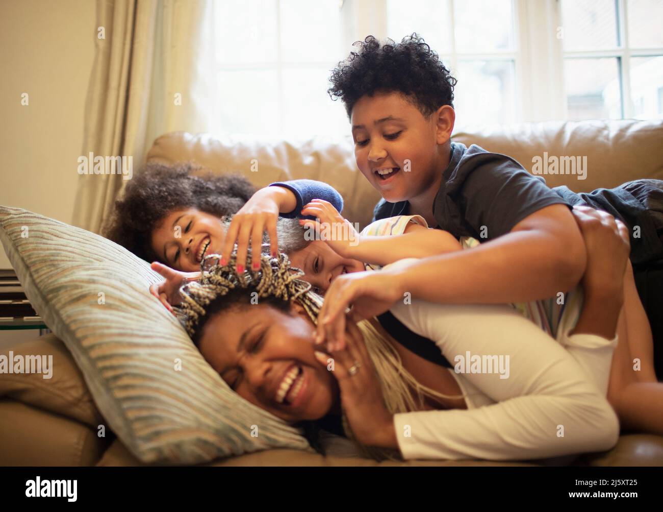 Mère et enfants joueurs sur le canapé du salon Banque D'Images