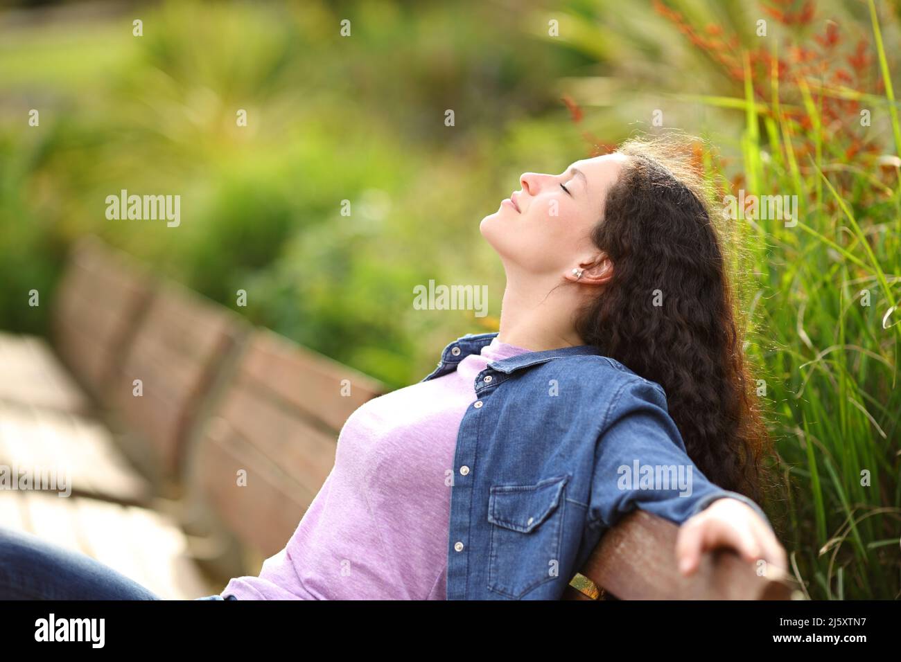 Profil d'une femme qui respire de l'air frais assis sur un banc dans un parc Banque D'Images