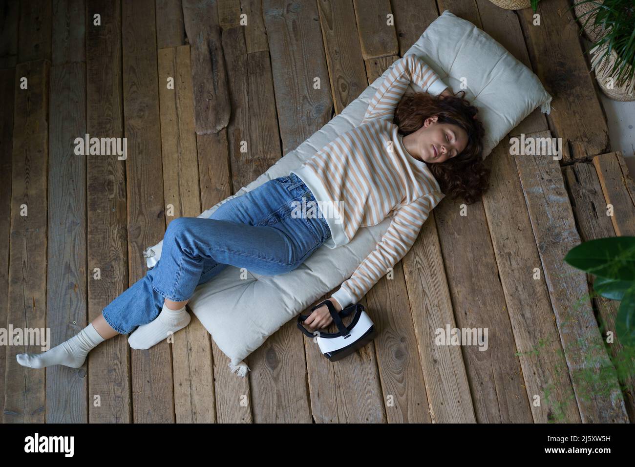 Femme millénaire détendue rêvant après avoir utilisé l'interface de réalité virtuelle, vue de dessus Banque D'Images