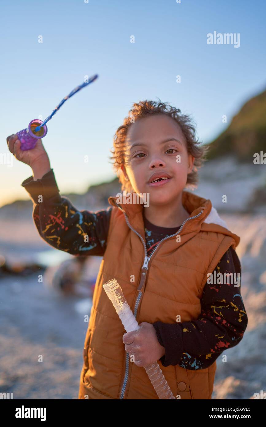 Portrait mignon garçon avec le syndrome de duvet jouant avec baguette de bulle Banque D'Images