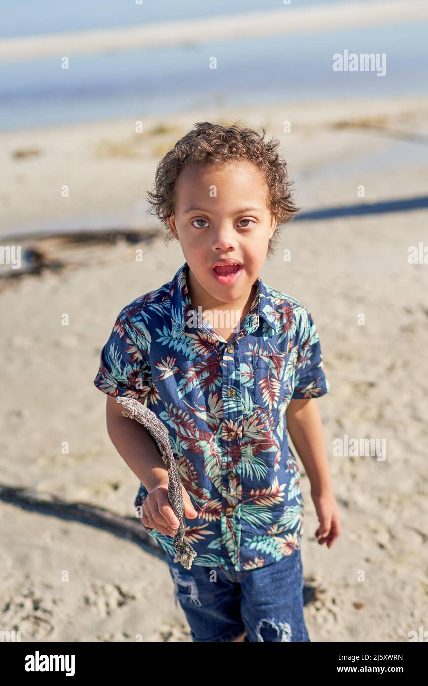 Portrait mignon garçon avec le syndrome de Down tenant bâton sur la plage Banque D'Images