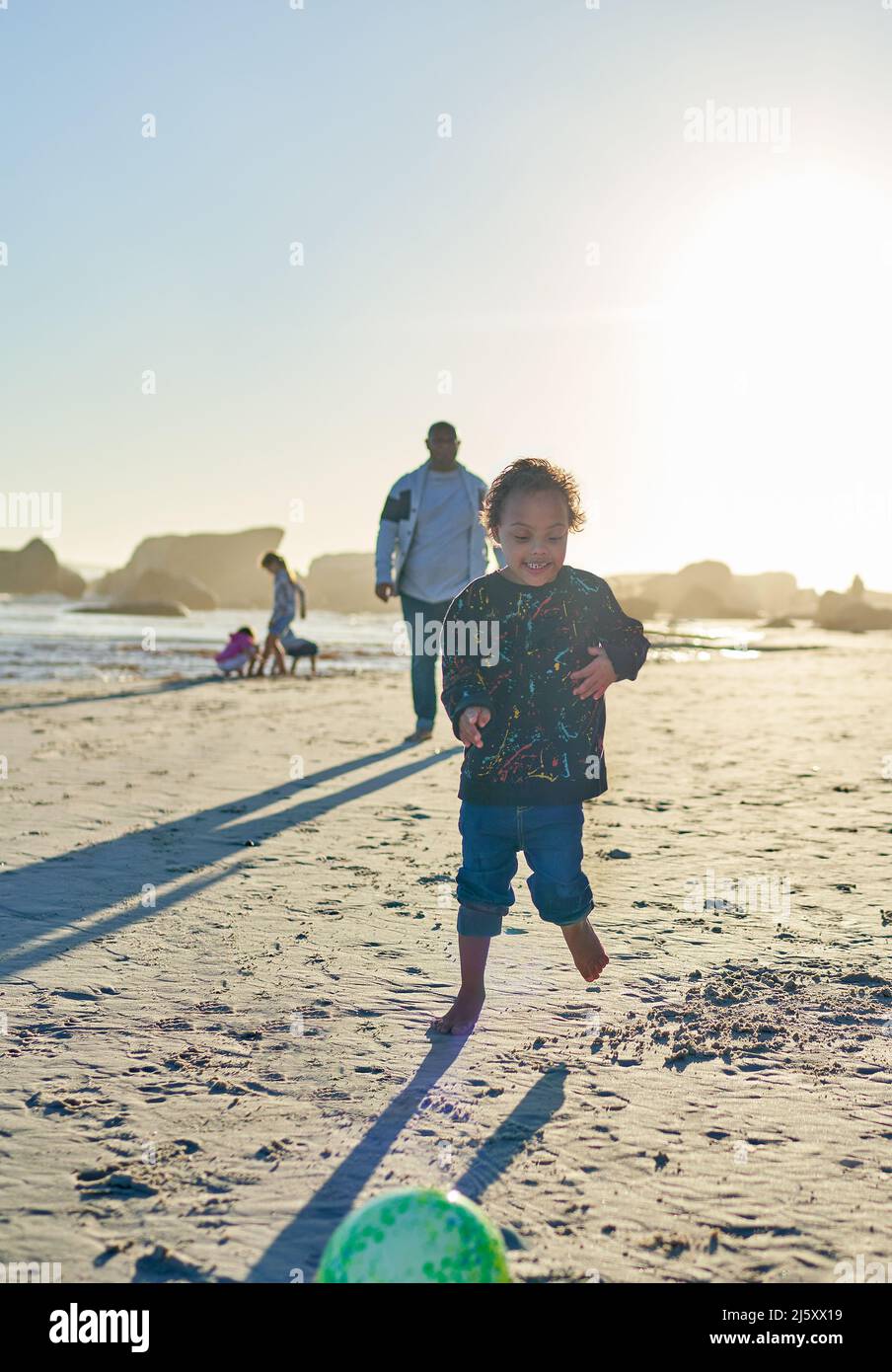 Insouciant garçon avec le syndrome de Down jouant sur la plage ensoleillée Banque D'Images