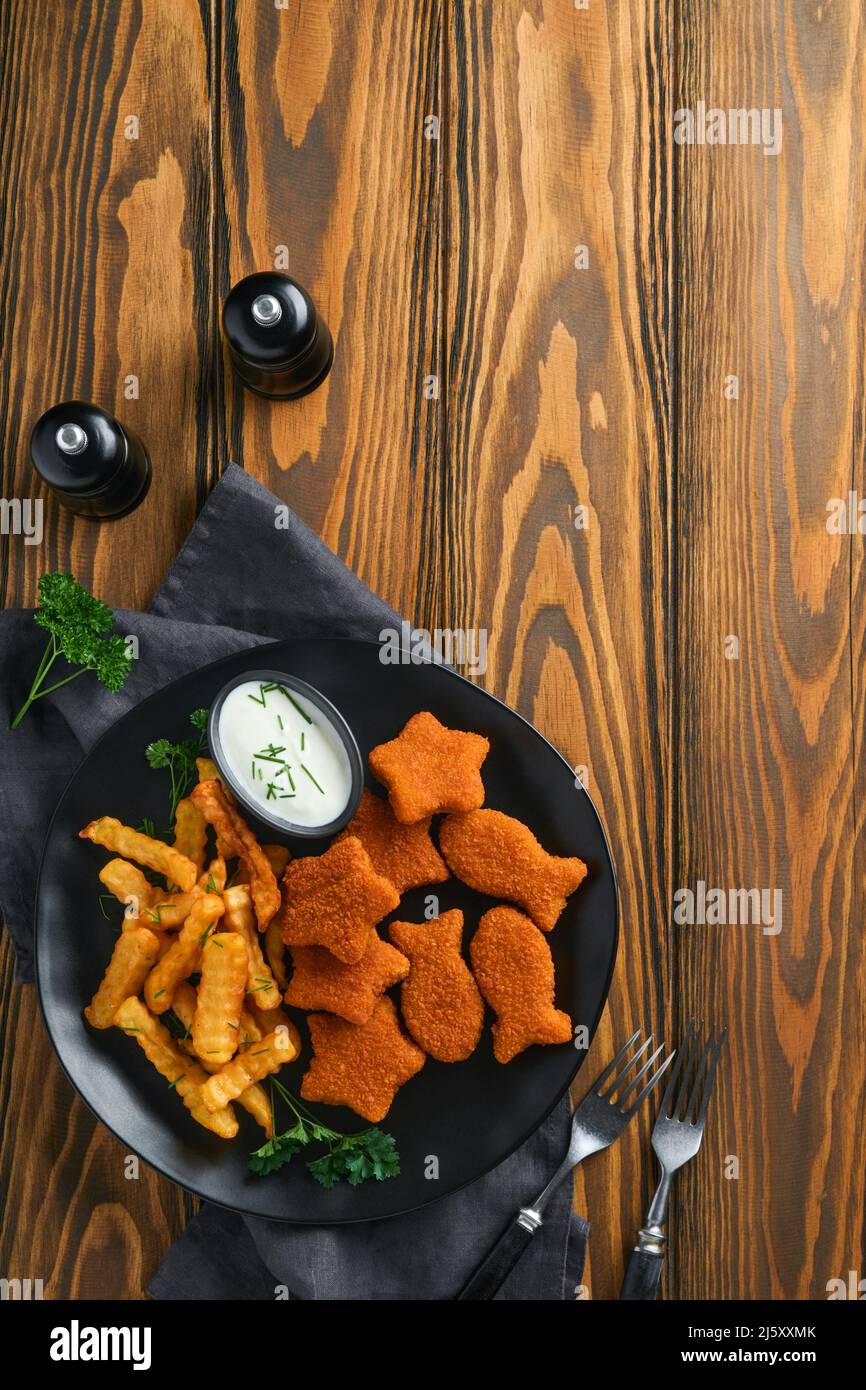 Fish and Chips, restauration rapide britannique. Bâtonnets de poisson avec frites sur plaque noire sur fond de table en bois. Plat traditionnel britannique authentique Banque D'Images