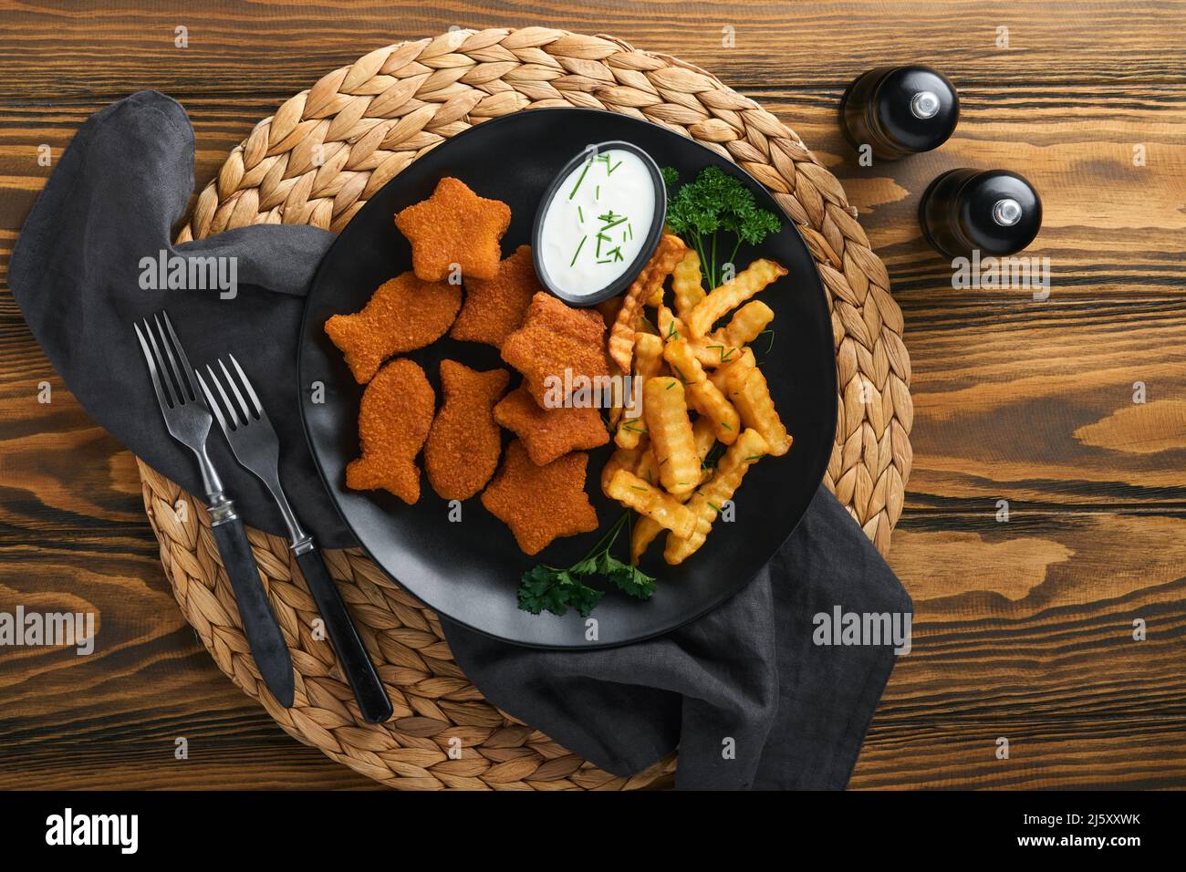 Fish and Chips, restauration rapide britannique. Bâtonnets de poisson avec frites sur plaque noire sur fond de table en bois. Plat traditionnel britannique authentique Banque D'Images