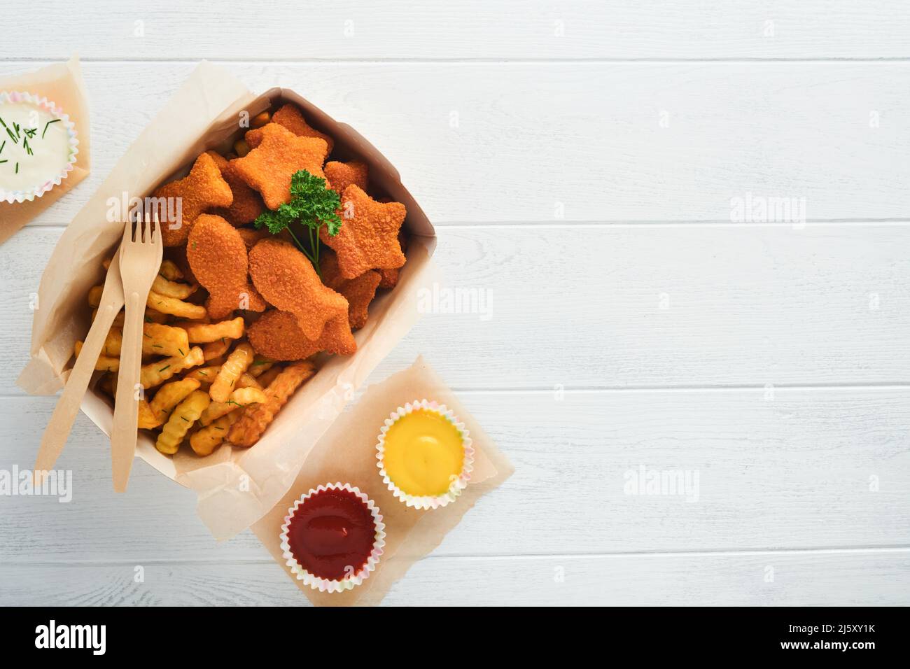 Fish and Chips, restauration rapide britannique. Bâtonnets de poisson avec frites sur une assiette en papier à emporter sur fond en bois blanc. Authentique britannique traditionnel Banque D'Images