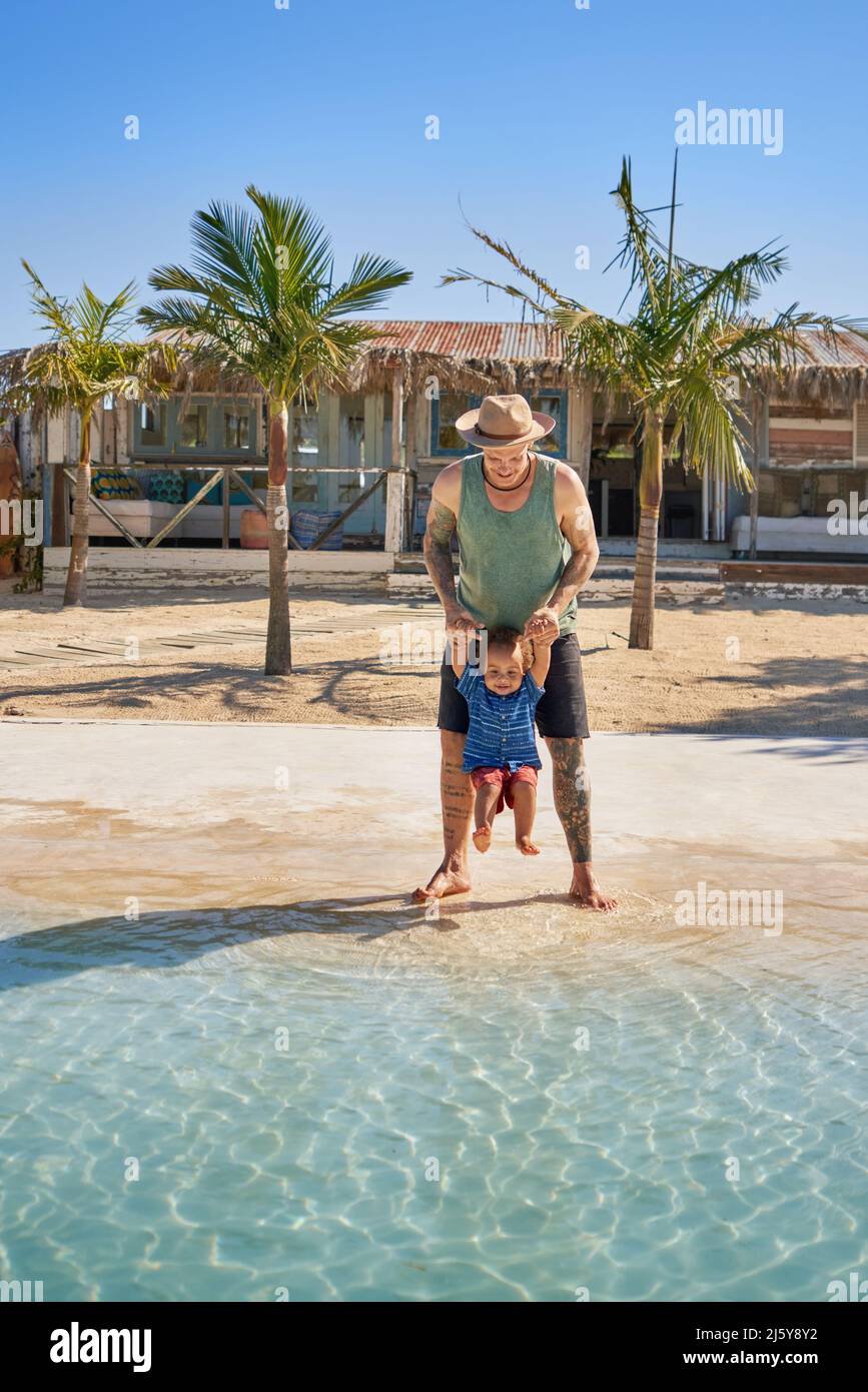 Père et petit fils mignon jouant dans l'océan d'été ensoleillé Banque D'Images