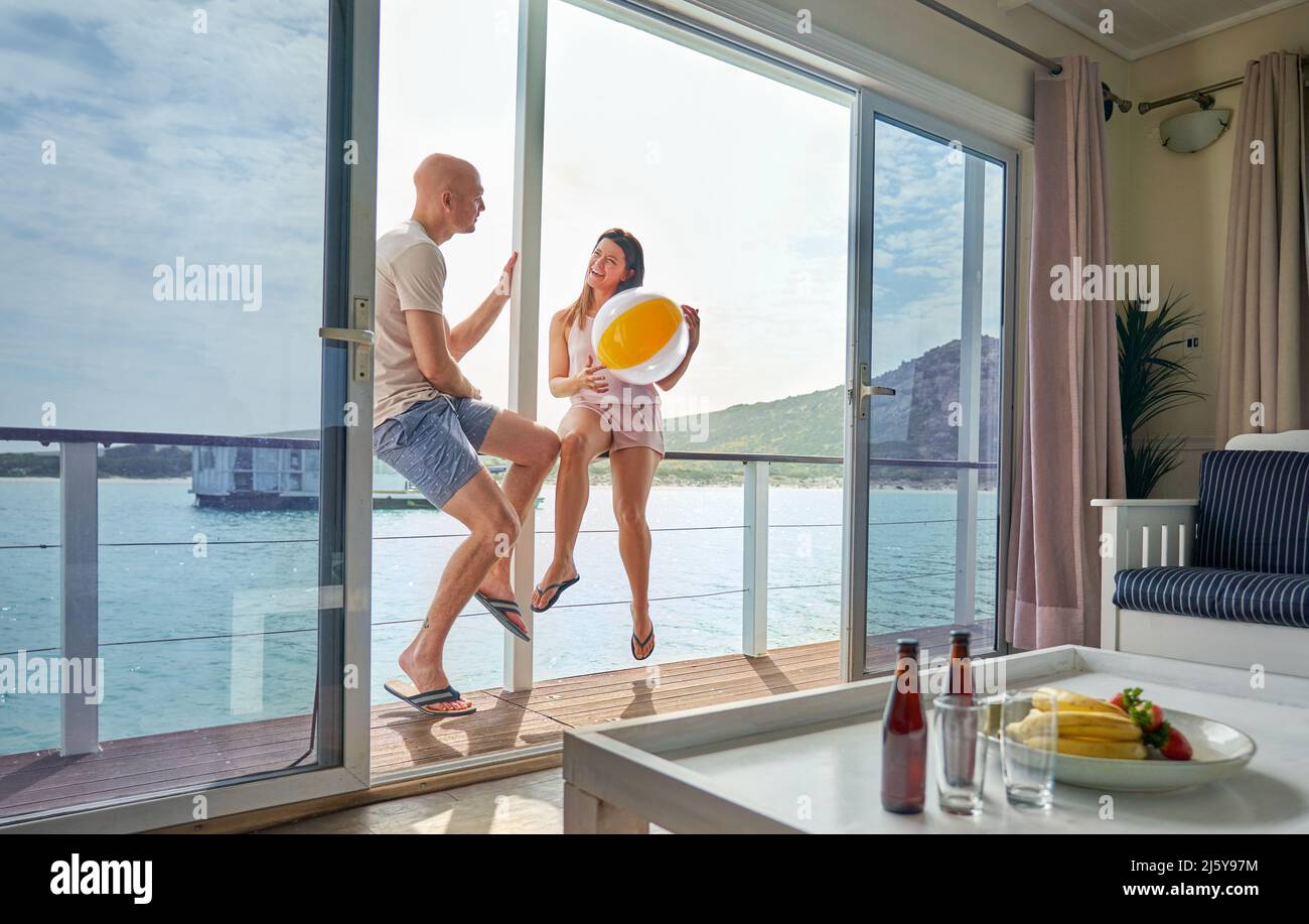 Couple heureux avec ballon de plage sur la terrasse de péniche sur le lac ensoleillé Banque D'Images