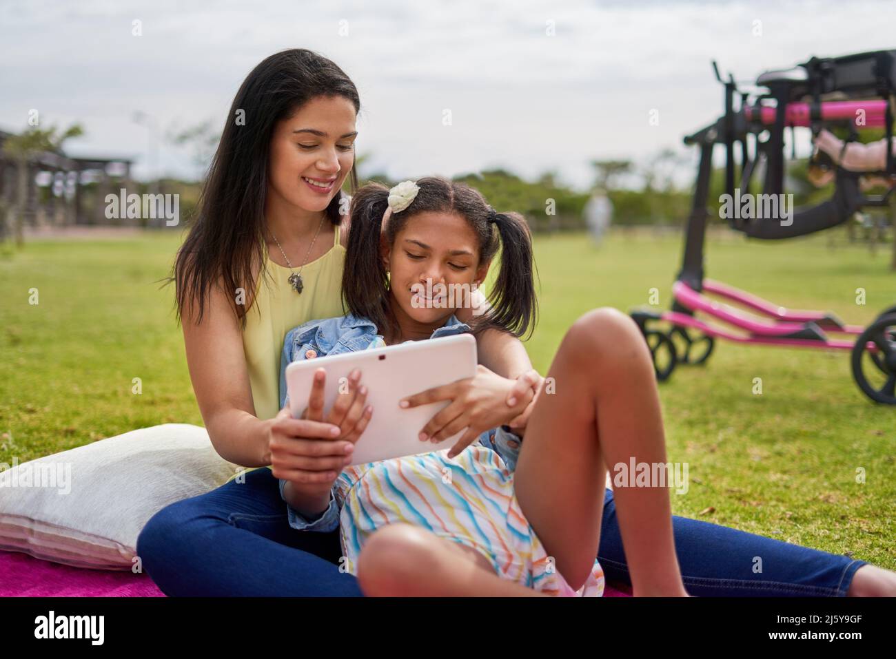 Mère et fille handicapée utilisant une tablette numérique sur une couverture dans le parc Banque D'Images