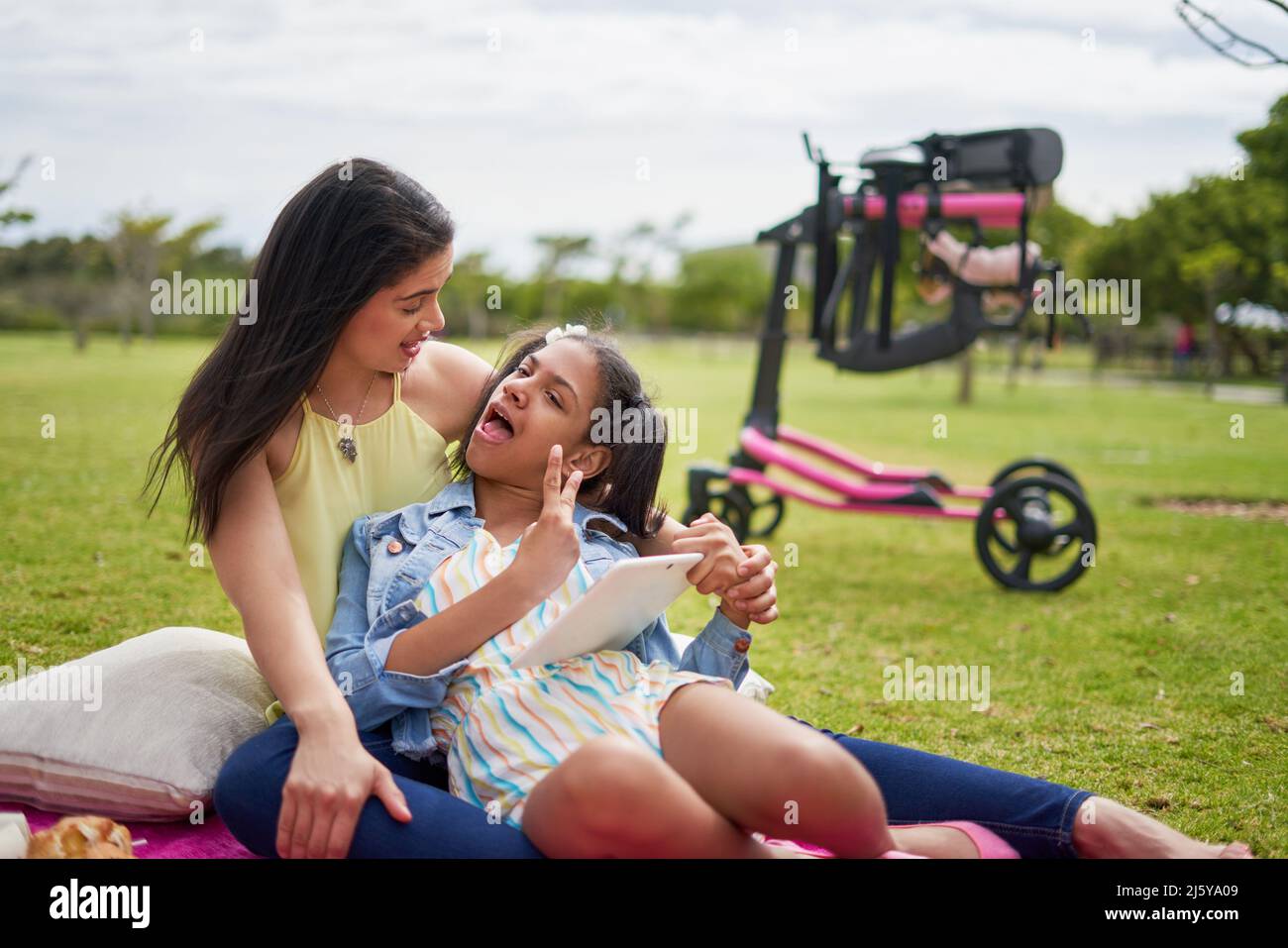 Mère et fille handicapée avec tablette numérique sur une couverture dans le parc Banque D'Images