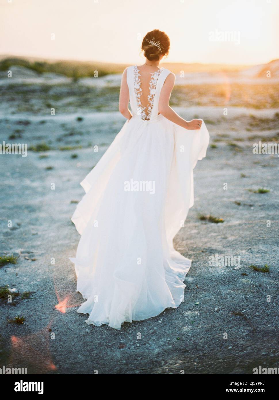 Mariée en robe de mariage blanche court sur le coucher du soleil du désert, paysage d'été Banque D'Images