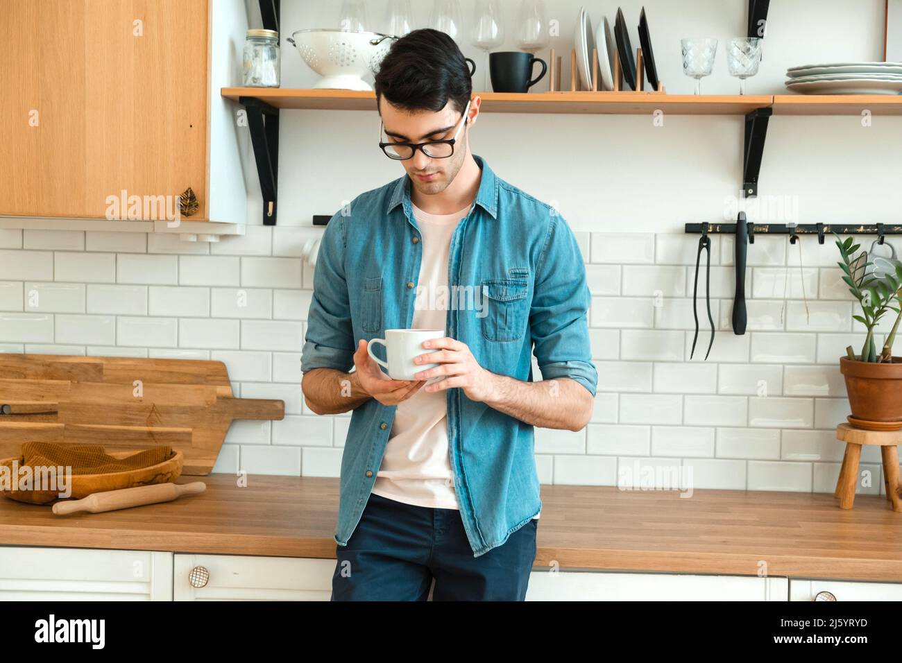 Seul un jeune homme éveillé et attentionné tient une tasse et boit le café du matin Banque D'Images