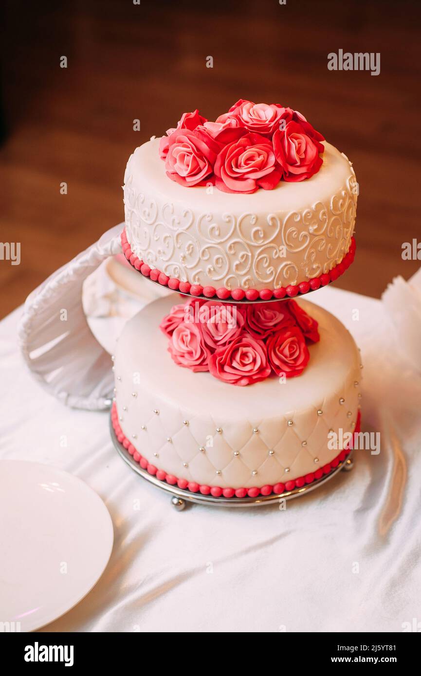 Gâteau de mariage blanc décoré de fleurs roses rouges. Inspiration classique de mariage rose Banque D'Images
