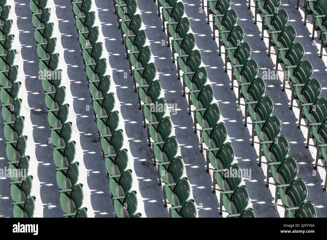 Des rangées de sièges verts vides lors d'un événement sportif en plein air par temps ensoleillé. Banque D'Images