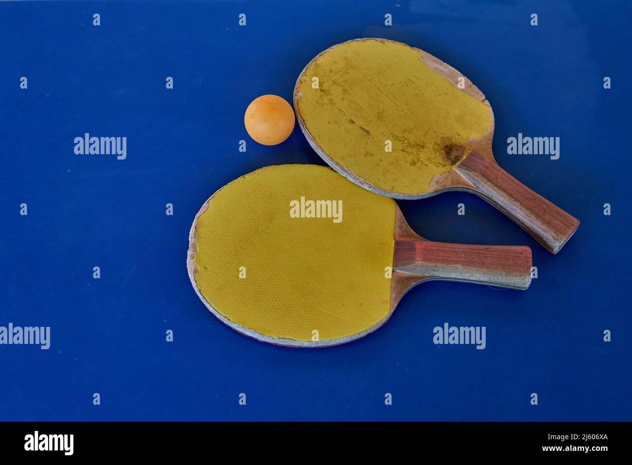 Raquettes de ping-pong jaunes et boule orange sur table bleue, plat. Espace de copie, horizontal Banque D'Images