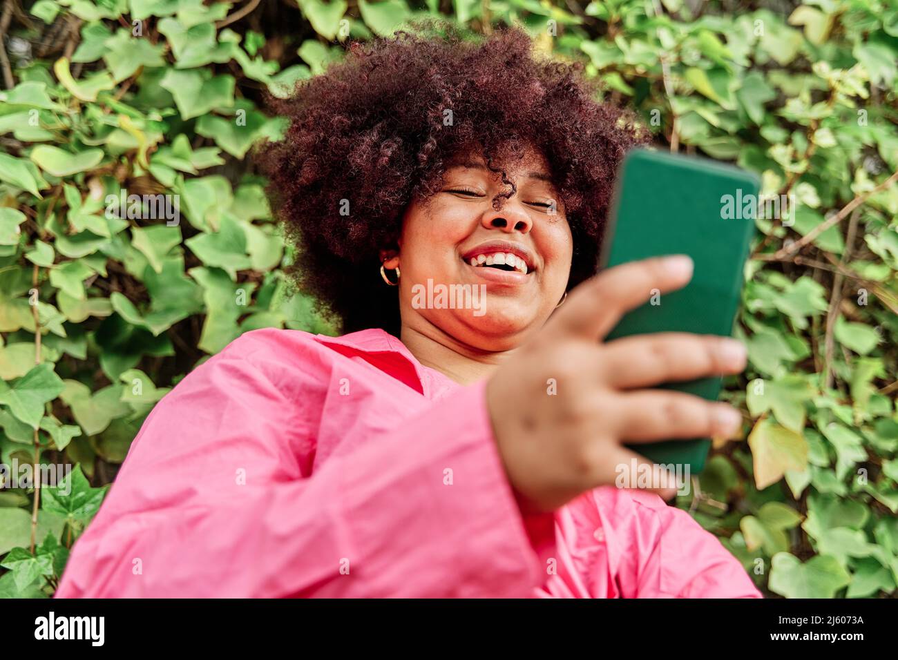 jeune femme aux cheveux bouclés utilisant son smartphone. portrait d'une femme afro-américaine utilisant les médias sociaux. Banque D'Images