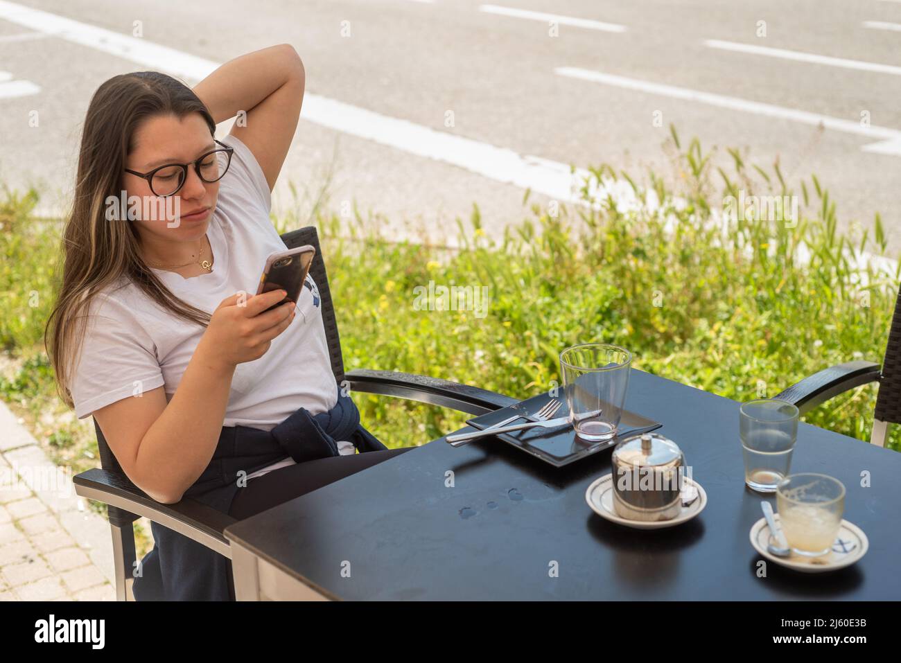 Cheveux longs latina jeune femme se reposant sur la terrasse d'été café-restaurant Banque D'Images