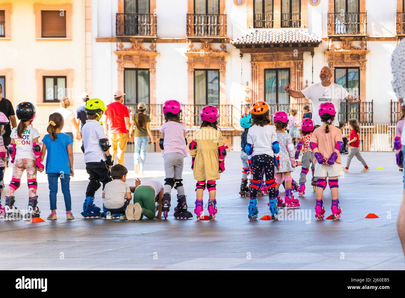 Les enfants en vêtements aux couleurs vives apprennent à faire du roller-skate avec un instructeur à Séville Séville espagne sous les Las Setas de Sevilla Banque D'Images