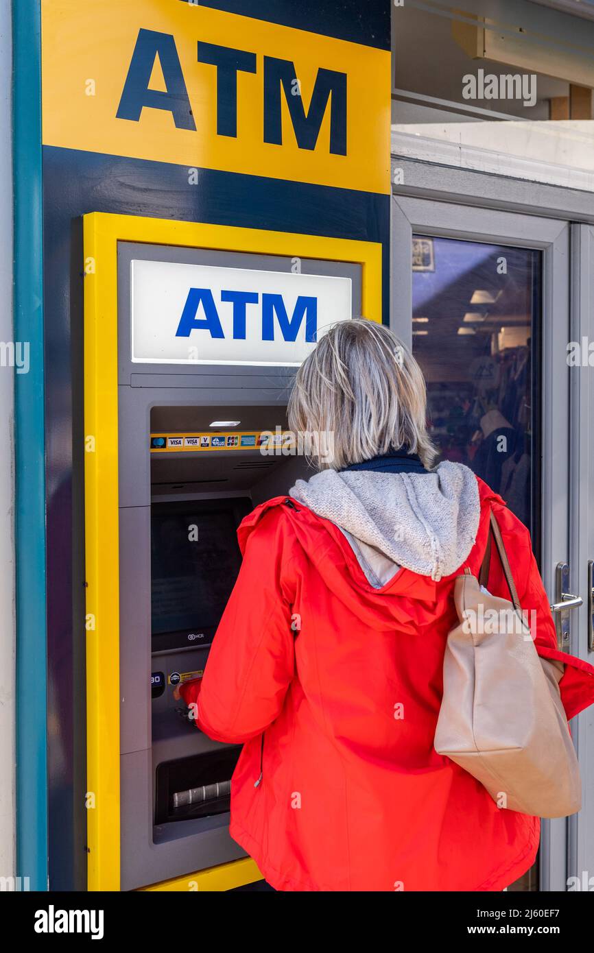 Femme utilisant un distributeur automatique de billets à Dingle, comté de Kerry, Irlande. Banque D'Images