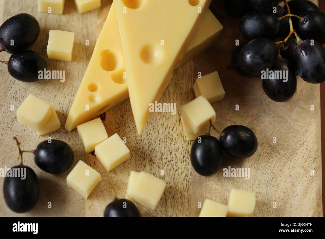 Fromage coupé avec des fruits.triangles de fromage Mazdar, cubes de fromage gouda et raisins noirs.fromage aux raisins baies sur bois background.milk de graisse et lait Banque D'Images