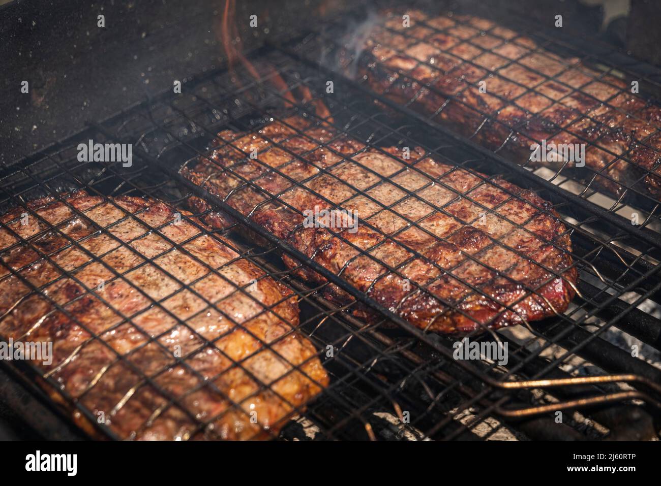 Mise au point sélective de steaks de bœuf juteux grillés sur grille barbecue avec fumée Banque D'Images