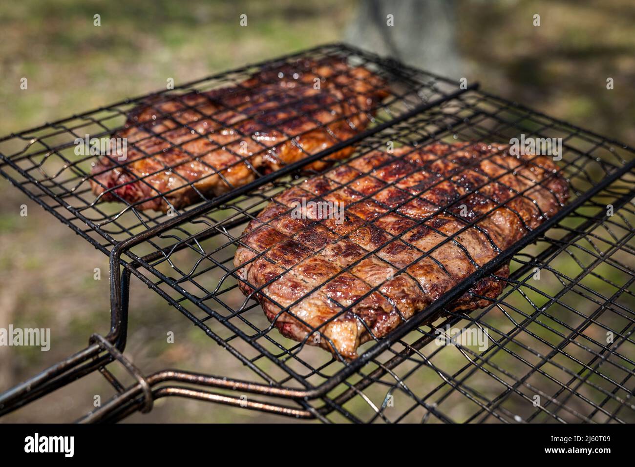 Mise au point sélective de steaks de bœuf juteux grillés sur grille barbecue avec fumée Banque D'Images