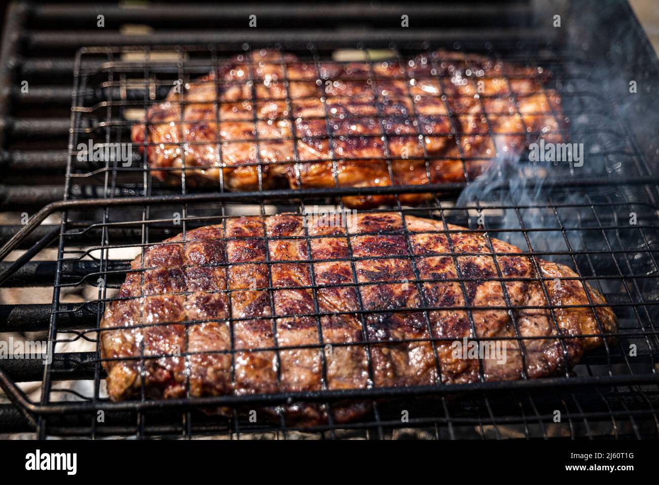 Mise au point sélective de steaks de bœuf juteux grillés sur grille barbecue avec fumée Banque D'Images