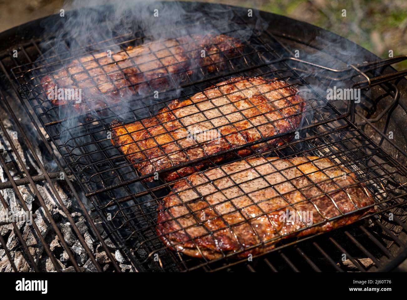 Mise au point sélective de steaks de bœuf juteux grillés sur grille barbecue avec fumée Banque D'Images
