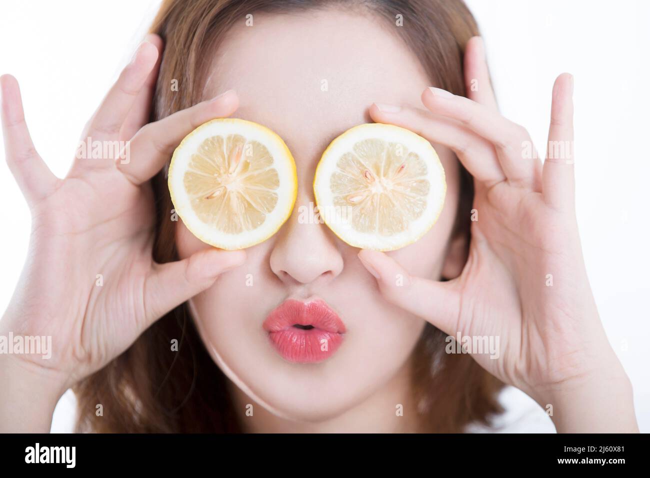 Jolie jeune dame a couvert ses yeux avec une tranche de citron, sur fond blanc - photo de stock Banque D'Images