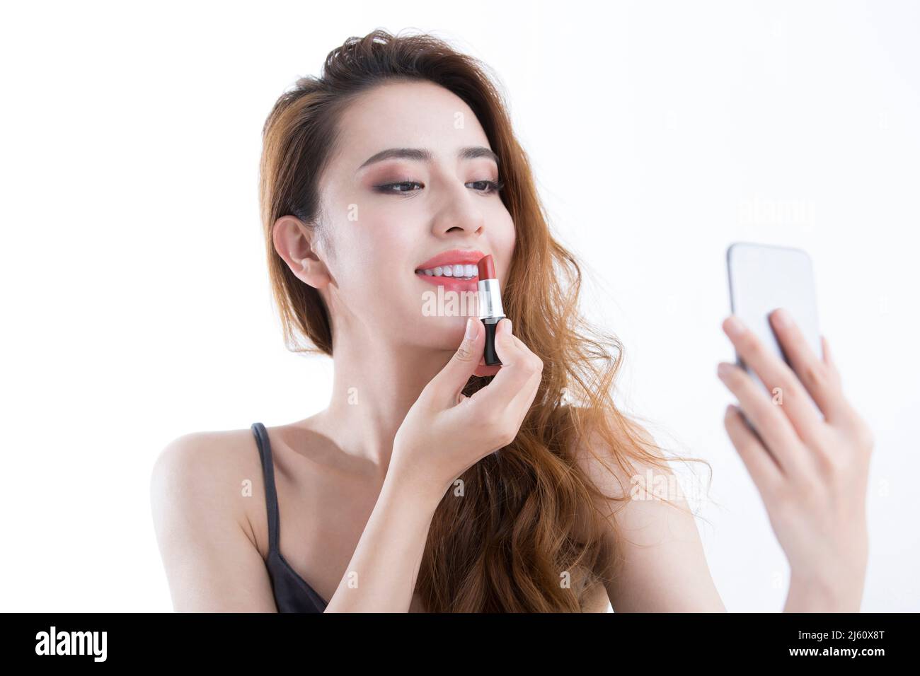 Belle jeune femme appliquant le rouge à lèvres avec un miroir de maquillage, sur fond blanc - photo de stock Banque D'Images