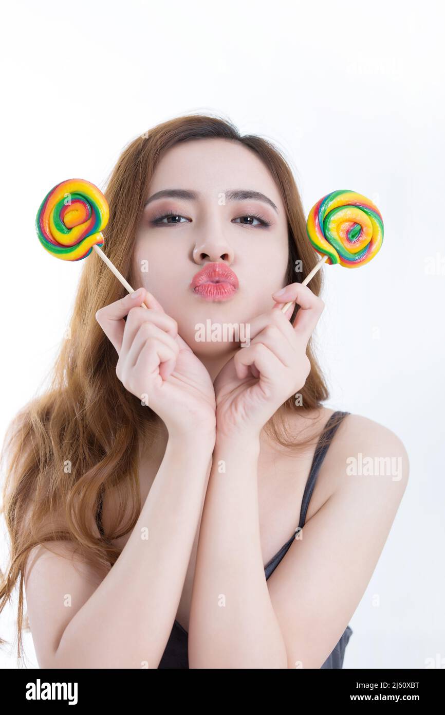 Belle jeune femme a montré deux sucettes colorées, sur fond blanc - photo de stock Banque D'Images